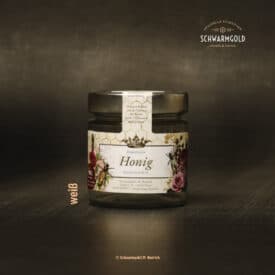 Honigglas mit Etikett auf dunklem Hintergrund.